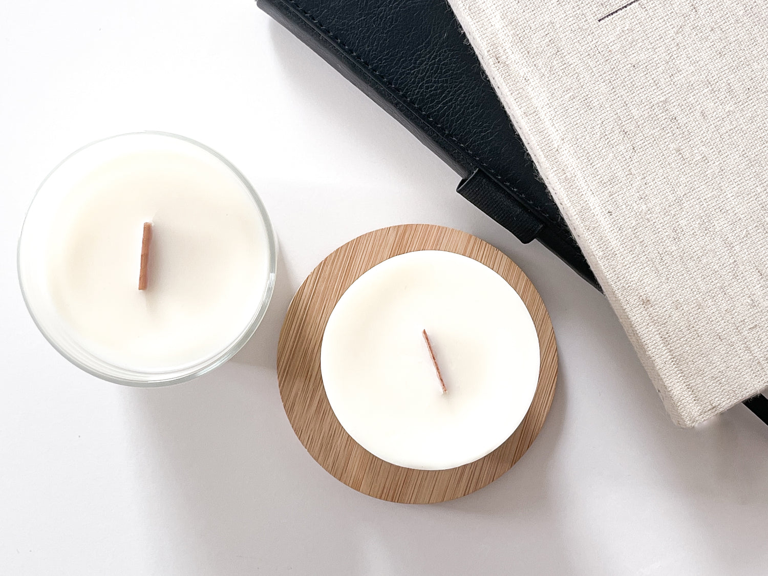 Une bougie LUA et sa recharge en décoration sur table en fond blanc, ainsi que deux livres de chevet